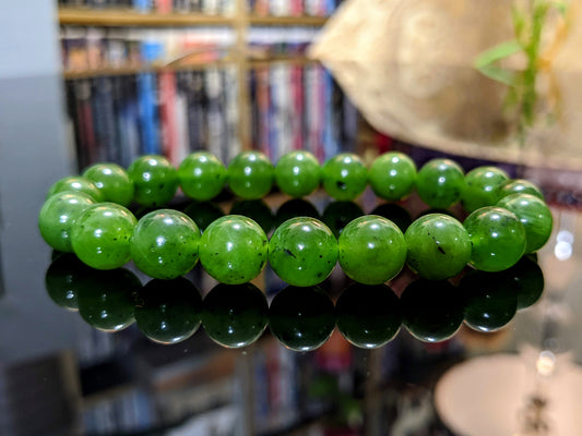This is the main picture for the natural Kutcho Canadian Jade bead bracelet.  The bracelet is made of 10 mm size beads, and it is displayed on a flat black surface.  The Jade is excellent. 