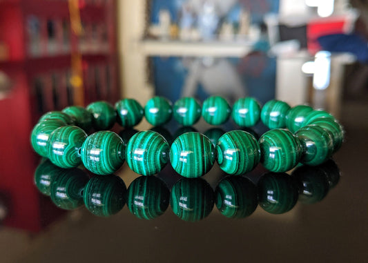 This is the main picture for the natural Malachite bead bracelet.  It is displayed on a smooth flat black surface.  Its striations and green color is superb.