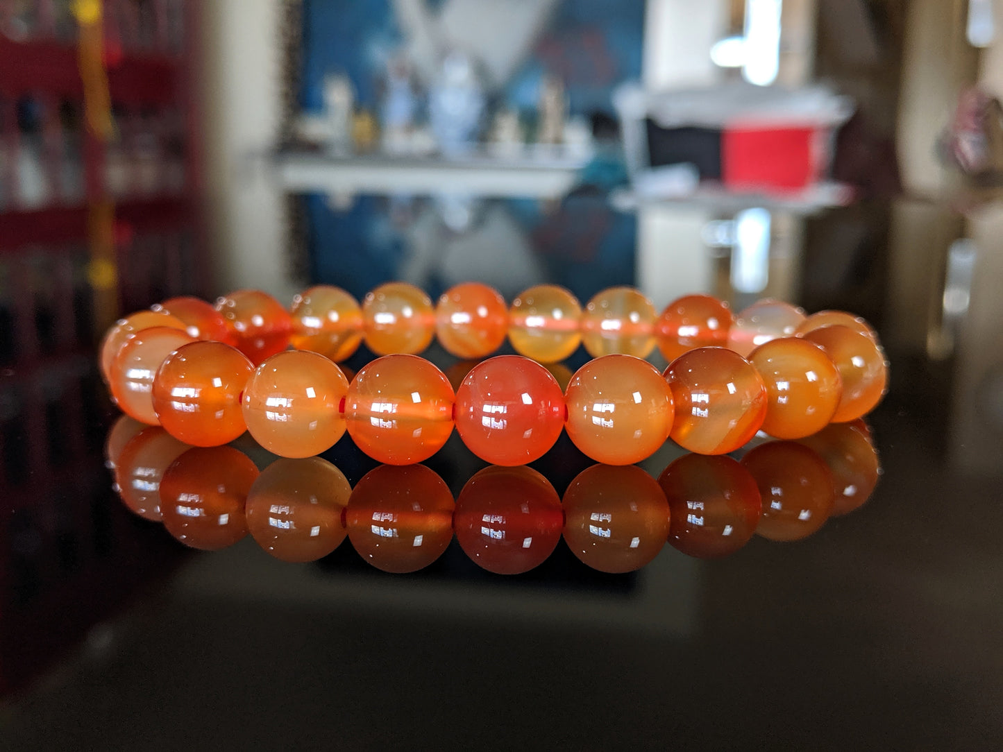 This is the main picutre for the Natural 
Carnelian bead bracelet.  The bracelet is displayed on a flat black surface, and the beads vary from white to different hues of orange.  It is a very energizing and inspirational stone.