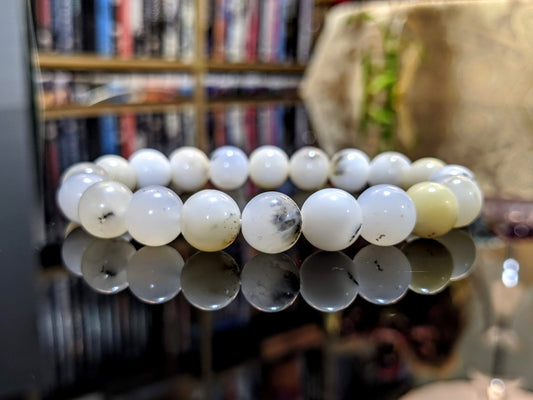 This is the main picture for the Dendritic Opal bead bracelet 10mm.  It is illustrated on a black flat surface.  The color varies, but mainly it is a milk white bead with some black. 100% Natural from Australia, and it is excellent. 