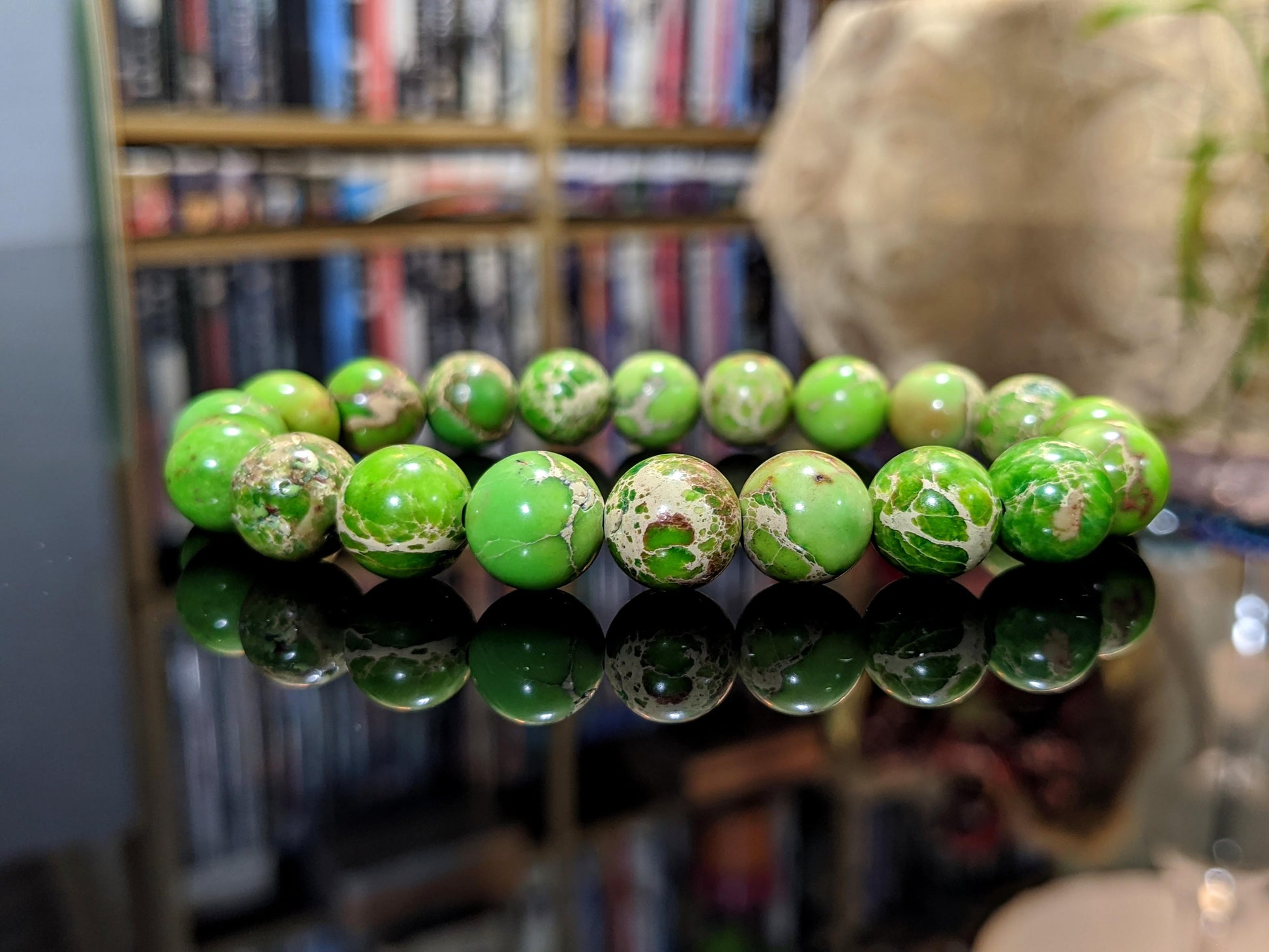 This is the main picture for the Kikuyu Green Sea Sediment bead bracelet.  The bracelet is displayed on a flat black surface.  The beads are marbilized with white and brown colors.  