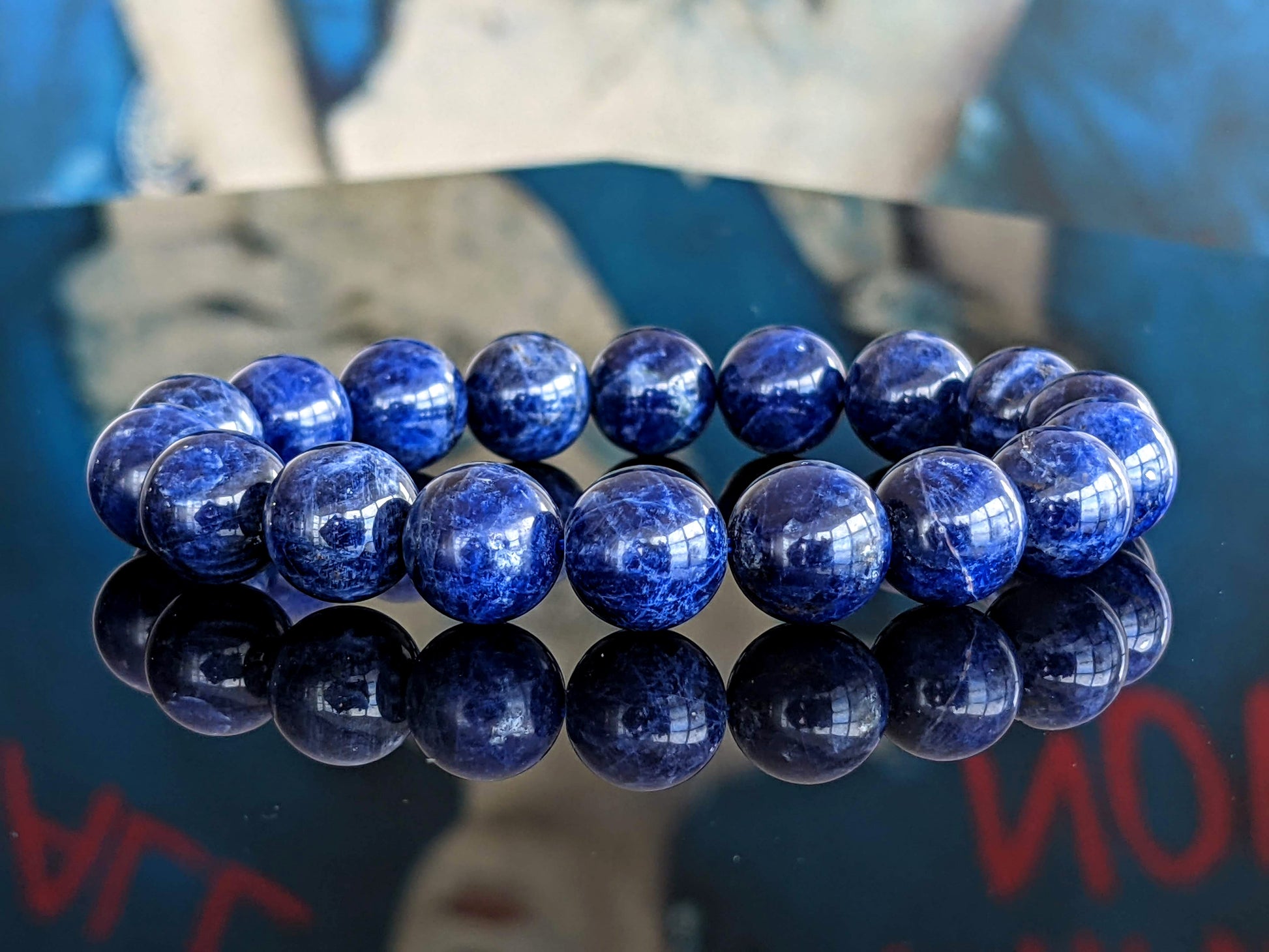 This is the main picture for the Blue Sodalite bead bracelet.  It is made with 12mm size beads and on durable red stretch cord.  The quality is the best on the market.  The bracelet on this picture is placed on a black flat surface to illustrate its true color.   It is excellent. 