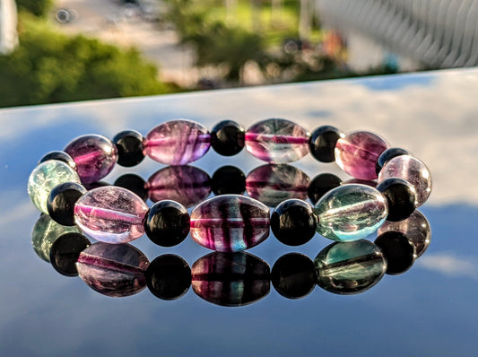 This is the main picture for the Multicolor Fluorite and Black Tourmaline bead bracelet.  The bracelet is displayed on a black surface.  It is our top selling product with outstanding craftmanship.  Every bead is hand selected for esthetics and beauty.  