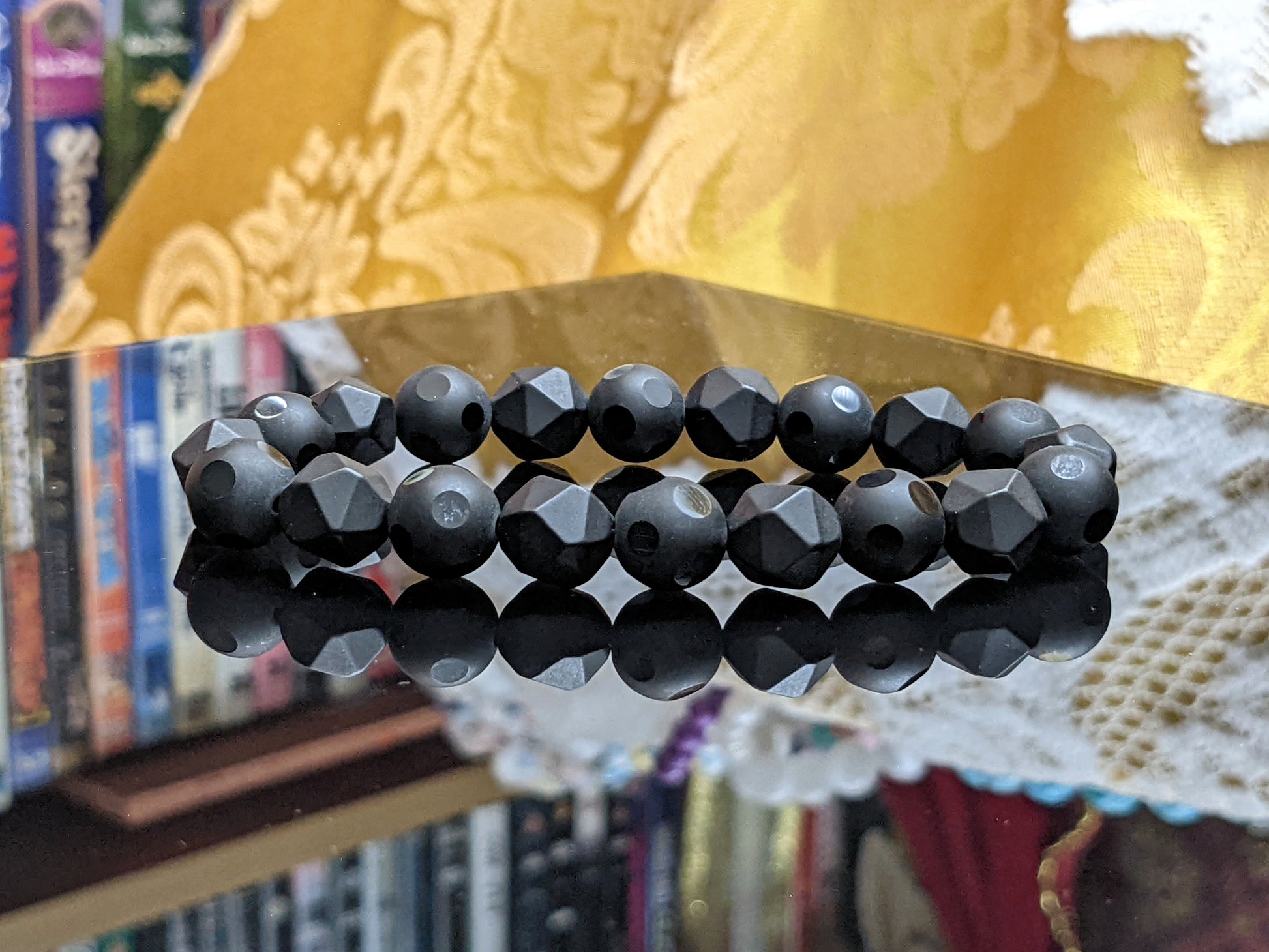 This is the main picture for the Matte Onyx facetted bead bracelet.  it is set on a smooth flat black surface with a yellow background.