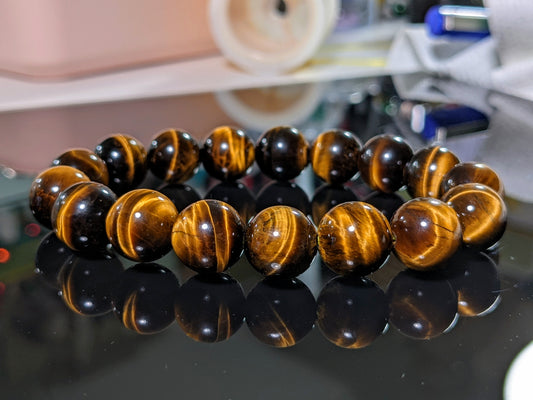 This is the main picture for the Yellow Tiger Eye bead bracelet 12mm.  The Yellow Tiger Eye is of 2A+ quality; excellent grade.  The bracelet is displayed on a flat black surface.  RayonBracelet.com