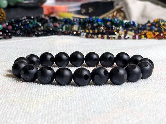 This is the main picture for the Dot Matte Black bead bracelet  The bracelet is displayed on a white surface.  It is excellent Onyx with facetted dots.  